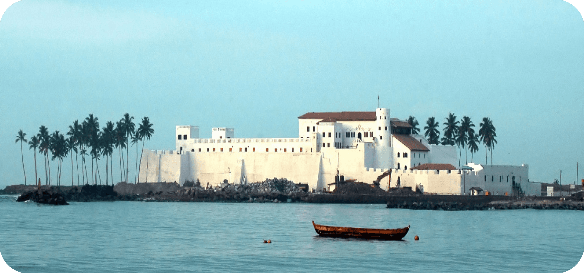 Elmina Castle in Ghana with palm trees and fishing boat